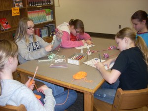 Girls weaving with yarn and drawing book marks.